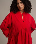 Una mujer talla XXL viste una blusa roja de manga larga con plisados hecha de cupro. La blusa es de la marca Yakampot, una firma de moda mexicana que fusiona tradición y modernidad . La blusa tiene un cuello redondo y un corte holgado que le da un toque de comodidad y estilo. La blusa es ideal para combinar con pantalones o faldas de colores neutros o contrastantes.