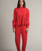Una mujer viste la blusa Montería roja de manga larga hecha de cupro y un pantalón rojo de corte recto con plisados de la marca Yakampot, moda mexicana que combina técnicas ancestrales con diseño contemporáneo